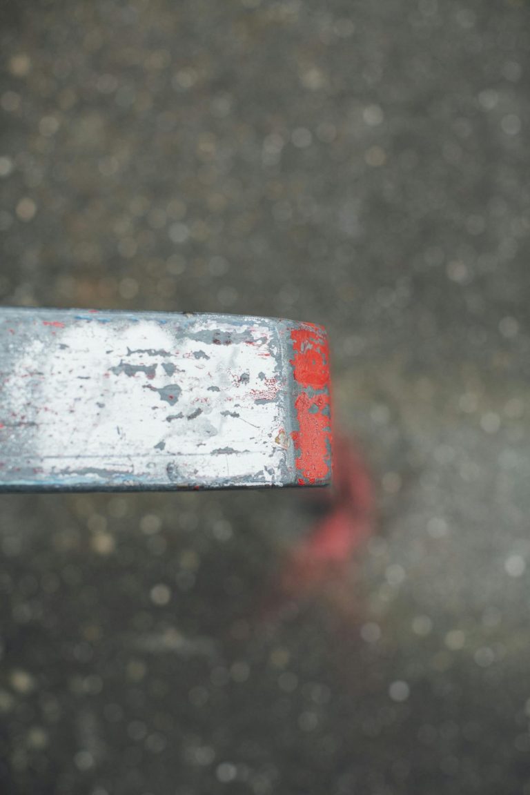 From above of industrial metal detail against blurred wet asphalt road in city