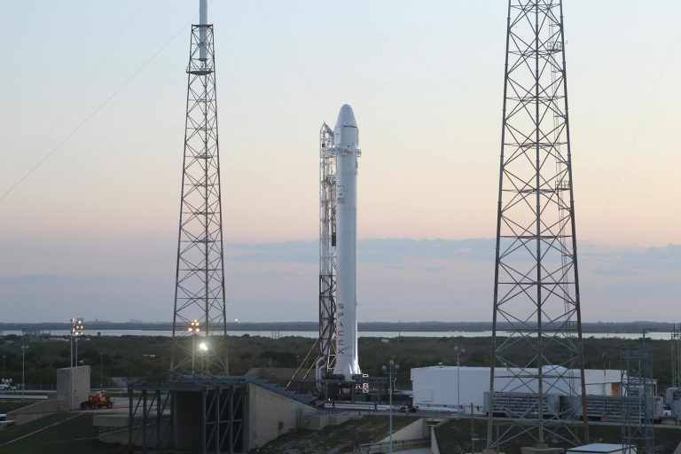 Space rocket installed on metal construction in spaceport and ready for launching against cloudless sky